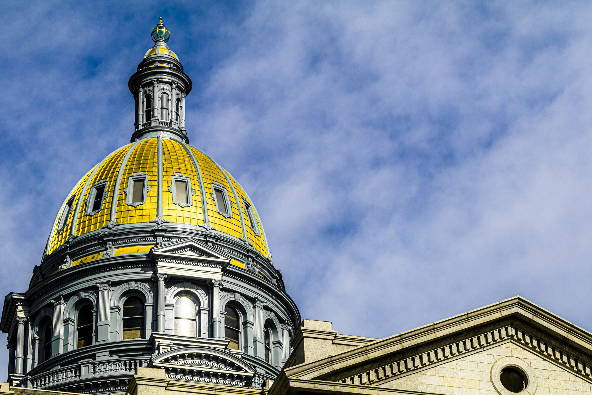 The Colorado State Capitol's gold dome against a blue sky.